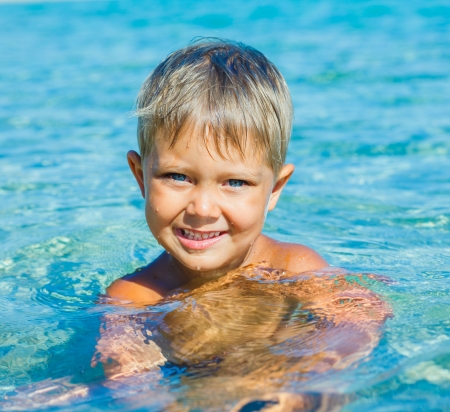 Portrait of young boy swimming in the transparent seaの写真素材
