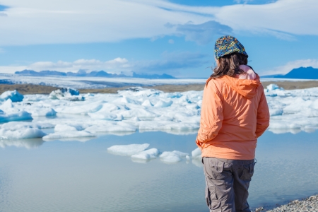 Young woman enjoying the view Jokulsarlon a lake in Iceland where icebergs collapsing from Vatnajokull glacier are floating around の写真素材