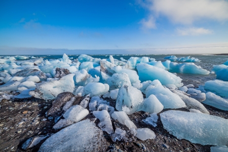 Beautiful beach in the South of Iceland with a black lava sand is full of icebergs from glaciers not far away の写真素材