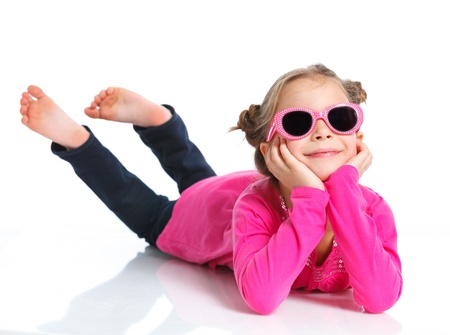 Little fashion girl lying in pink dress and sunglasses  Isolated white backround の写真素材