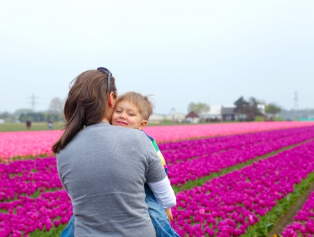 Little boy and his mother with bouquet between of the yellow-red tulips fieldの写真素材