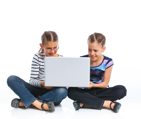 Two pretty young girls sitting on the floor with notebook  Isolated on white backgroundの写真素材