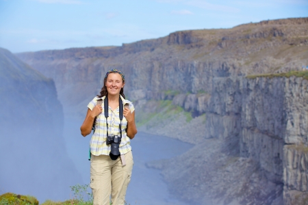 View of woman photographer standing near famous Dettifoss waterfall in Vatnajokull National Park, Northeast Icelandの写真素材