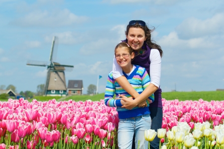 Cute girl and her mother between of the purple and white tulips fieldの写真素材