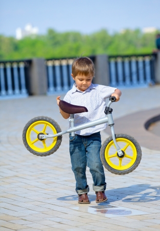 Little boy on a bicycle and his mother in the summer parkの写真素材
