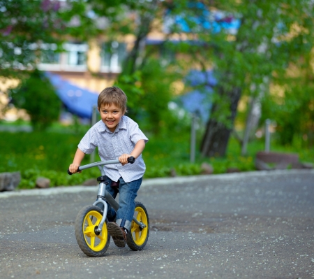 Little boy on a bicycle and his mother in the summer parkの写真素材