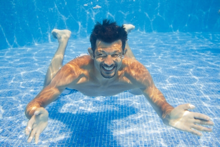 Man swimming in pool underwater and smilingの写真素材