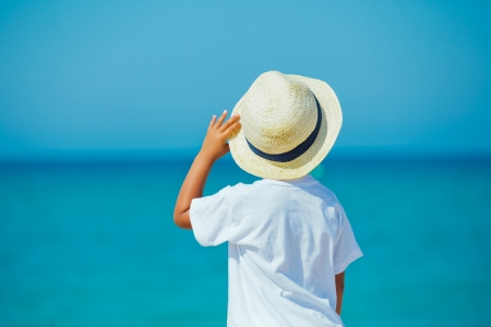 Back view of smiling cute boy in a sun hat at the tropical beach の写真素材