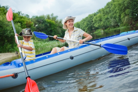 Happy young boy with mother paddling kayak on the river in lovely summer dayの写真素材