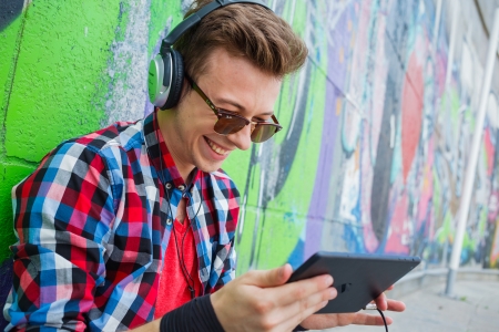Portrait of happy teens boy near painted wall listening to musicの写真素材