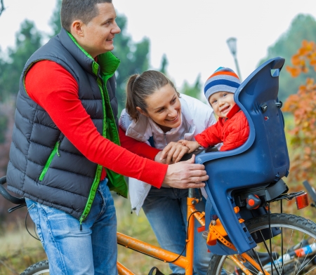 Family with baby on bikes in the autumn park の写真素材