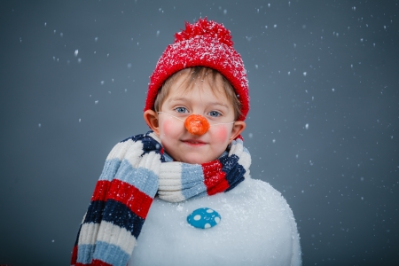 Portrait of cute little boy in suit snowman in red hat and scarfの写真素材