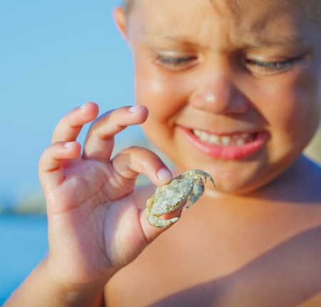 Adorable boy holding crab on hand on the beach  Focus on the crab の写真素材