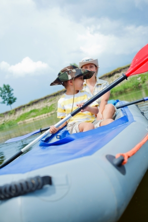 Happy little boy with mother paddling kayak on the river in lovely summer dayの写真素材