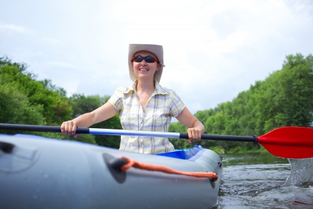 Happy woman paddling a kayak on the river, enjoying a lovely summer dayの写真素材