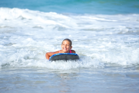 Summer vacation - Happy cute girl having fun with surfboard in the oceanの写真素材