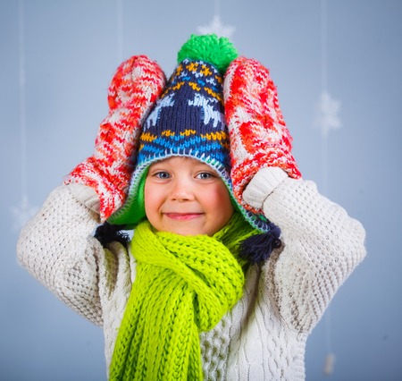 Winter Fashion  Portrait of adorable happy boy in winter hat gloves and sweater in studio の写真素材