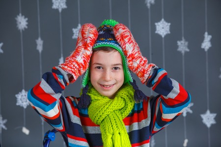 Winter Fashion  Portrait of adorable happy fashion boy in winter hat gloves and sweater in studio の写真素材