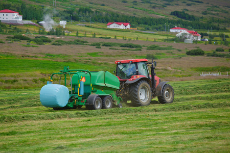 Huge tractor collecting haystack in the field  Iceland の写真素材