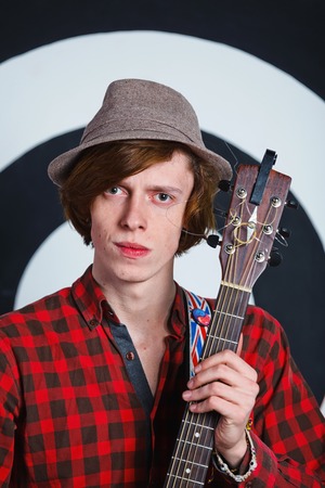 A musician  Portrait of emotional young handsome guy with a guitar in studio の写真素材