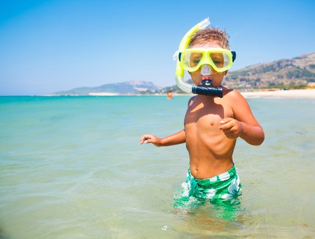 Summer vacation - Portrait of happy boy in face masks and snorkels, sea in background の写真素材