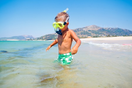 Summer vacation - Portrait of happy boy in face masks and snorkels, sea in background の写真素材