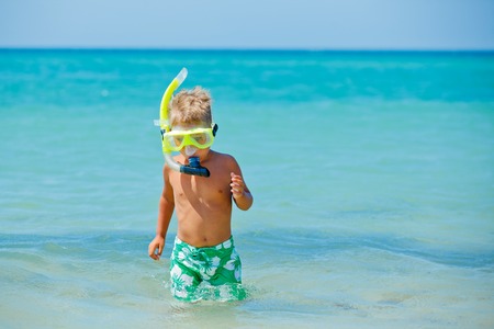 Summer vacation - Portrait of happy boy in face masks and snorkels, sea in background の写真素材