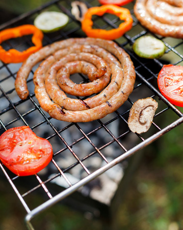 Barbecue on a hot day during the summer vacation on a green grass background. Meat and vegetables on the grill.の写真素材