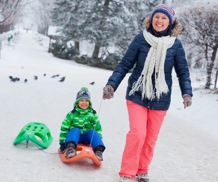 Family having fun with sled in winter parkの写真素材