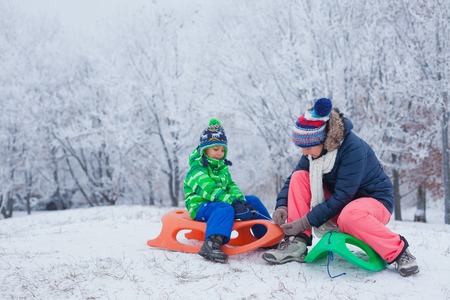 Family having fun with sled in winter park