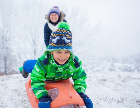 Little boy having fun with sled in winter parkの写真素材