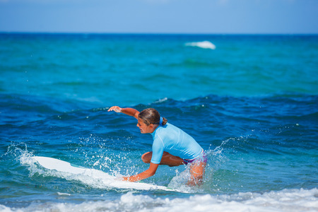 Teenage girl in blue learning to surfの写真素材