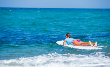 Teenage girl in blue learning to surfの写真素材