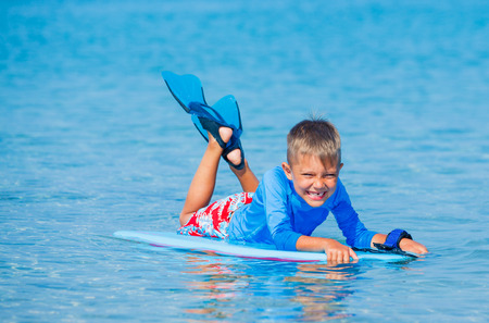 Little cute boy with surf board learning surfingの写真素材