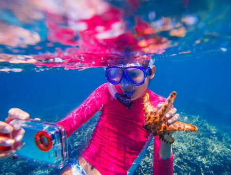 Underwater selfie photo of happy girl with a giant starfishの写真素材