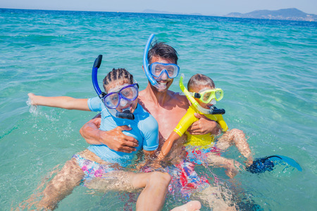 Joyful sister and brother with father scuba diving in the clear sea.の写真素材