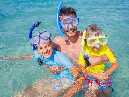 Joyful sister and brother with father scuba diving in the clear sea.の写真素材