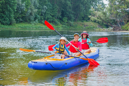 Active happy family. Boy with his sister and mother having fun together enjoying adventurous experience kayaking on the river on a sunny day during summer vacationの写真素材