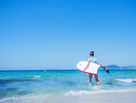 Happy Surfing girl on a beach ready to go into the water. Sunset time.