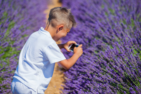 Happy boy take photo in lavender summer field near Valensole. Provence, France.の写真素材