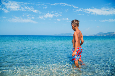 Back view of joyful boy looking at the clear sea.の写真素材