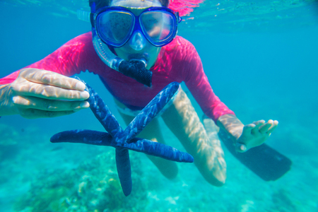 Underwater photo of happy girl with a giant starfishの写真素材