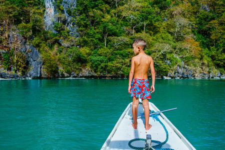 Joyful boy on the boat in tropical lagoon ready for diving.の写真素材