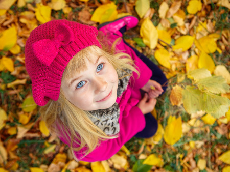 Very cheerful girl having fun with yellow leaves in autumn parkの写真素材