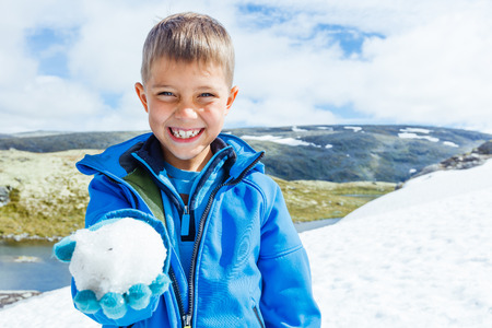Best Norway hike. Cute boy playing snow in the summer mountainsの写真素材