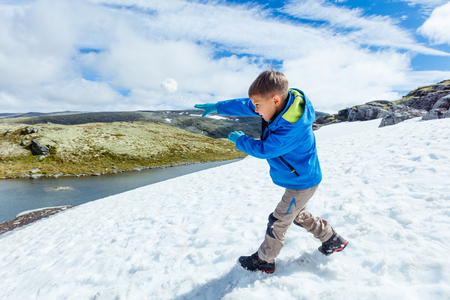 Best Norway hike. Cute boy playing snow in the summer mountainsの写真素材