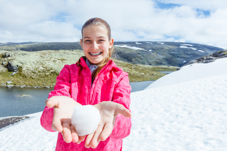 Best Norway hike. Beautiful girl play snow in the summer mountainsの写真素材