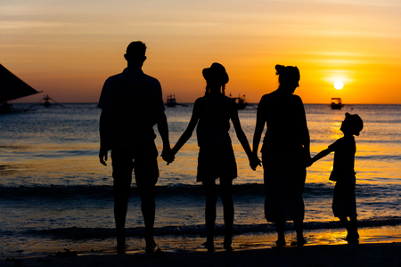 Silhouette of Happy family standing on the beach on the dawn timeの写真素材