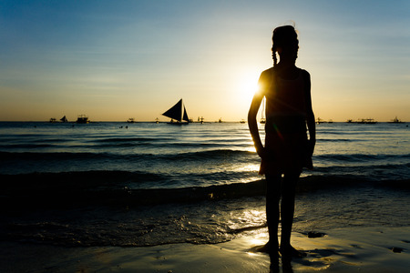 Silhouette of Happy girl on the beach on the dawn timeの写真素材