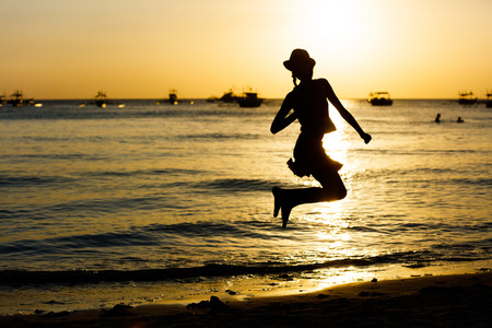 Silhouette of Happy girl jumping on the beach on the dawn timeの写真素材